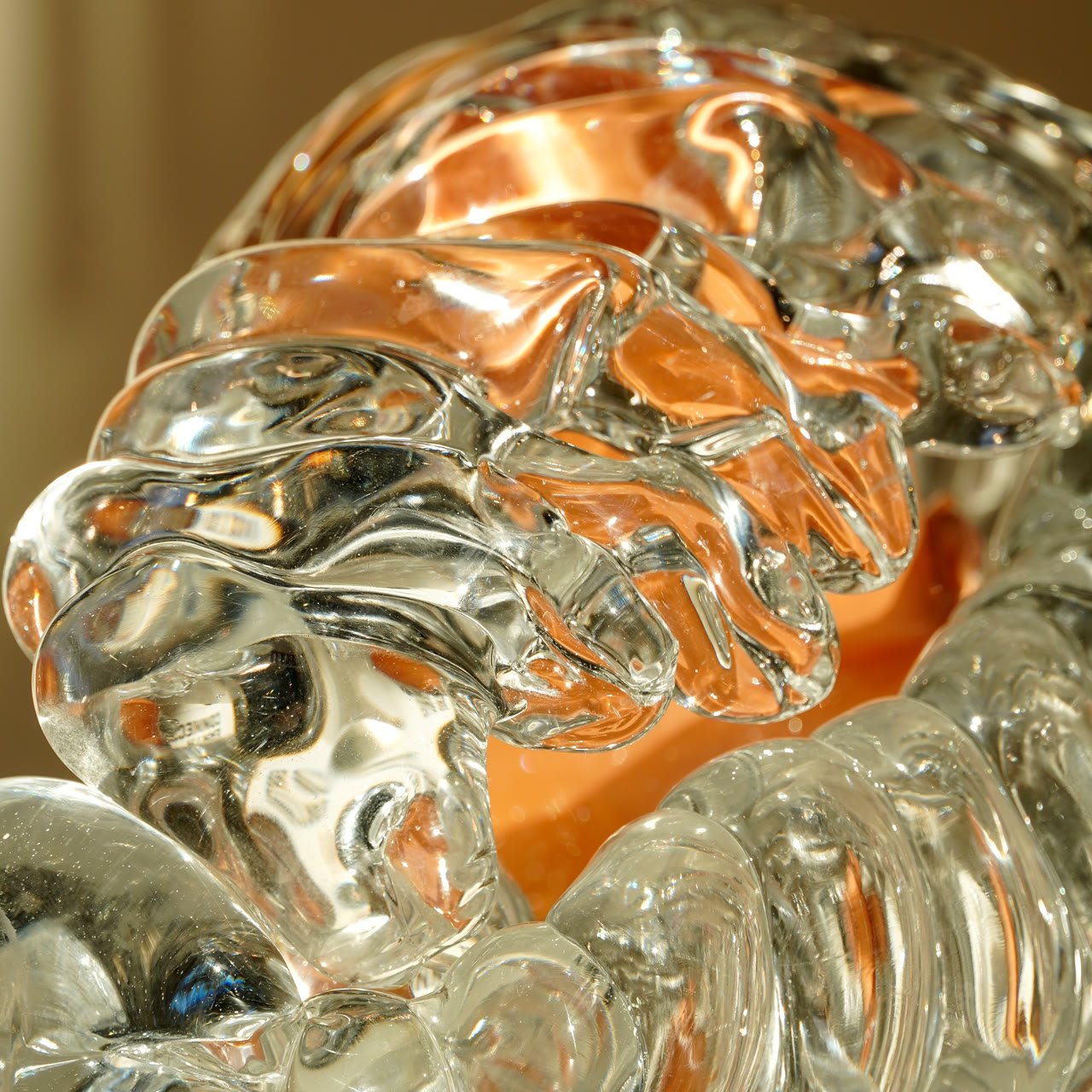Close detail of ribbed clear glass folds with amber glass glowing behind