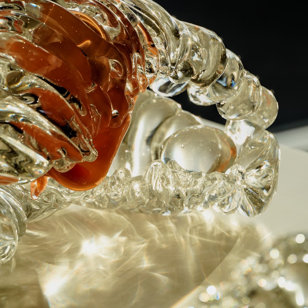 Close detail of amber-brown glass folds against clear ribbed glass