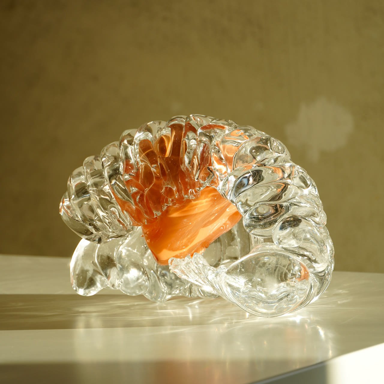 A ribbed clear glass shell with a vivid orange band across its opening