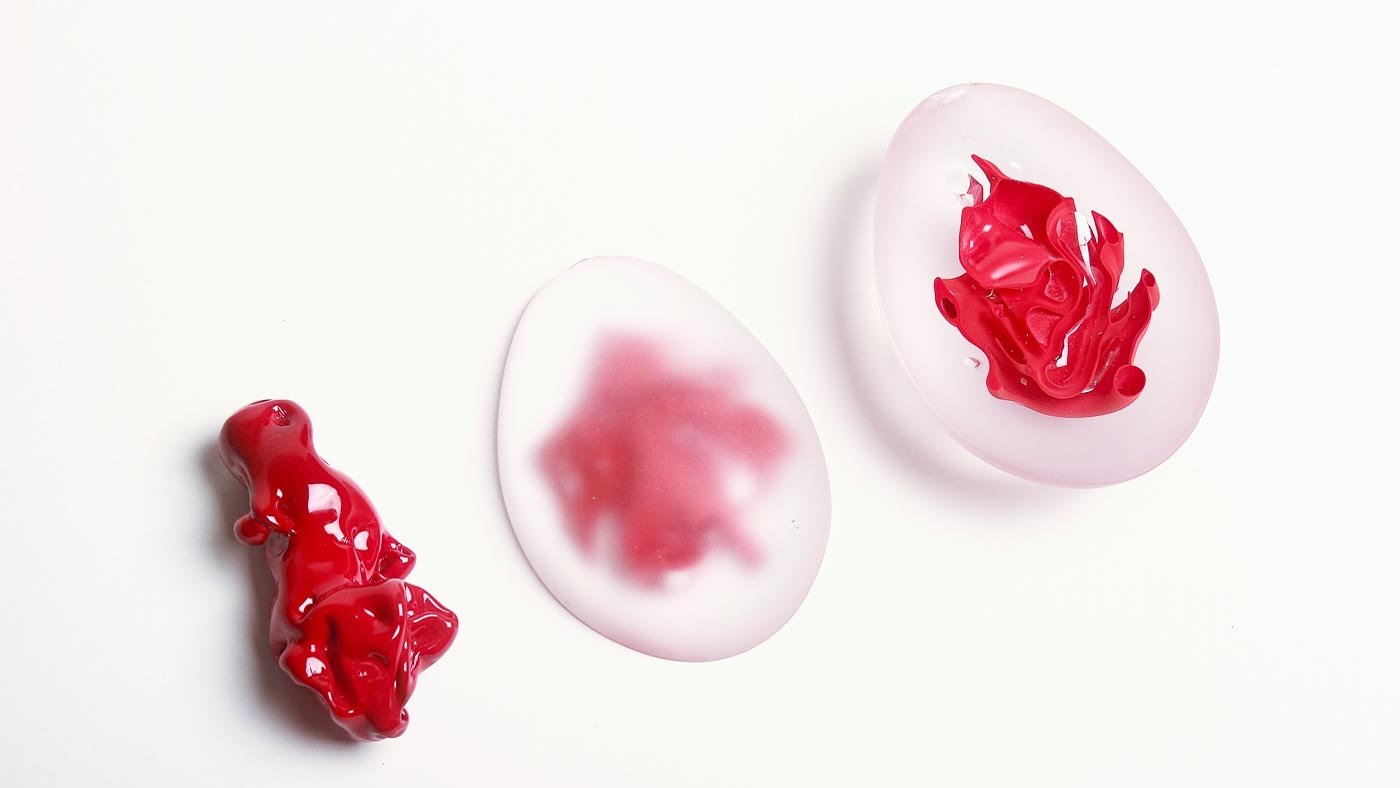 Three small pieces on white: a red shard, a pale disc, a frosted disc with a red ruffle