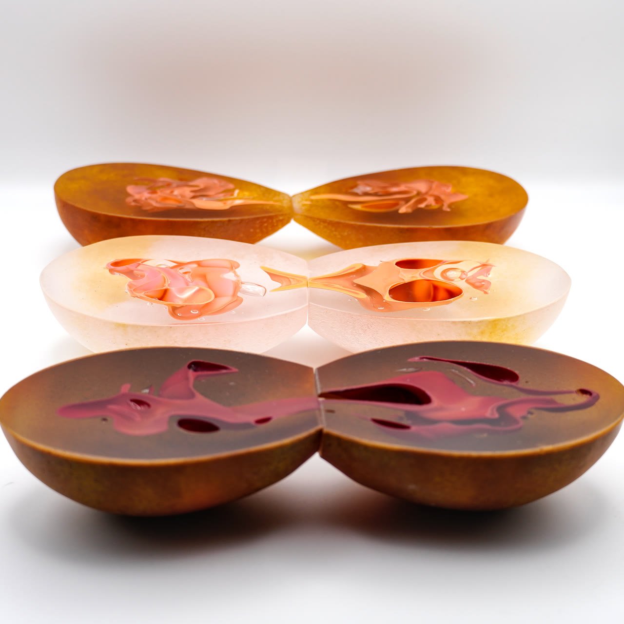 Three pairs of split frosted domes on white, in amber, white and bronze