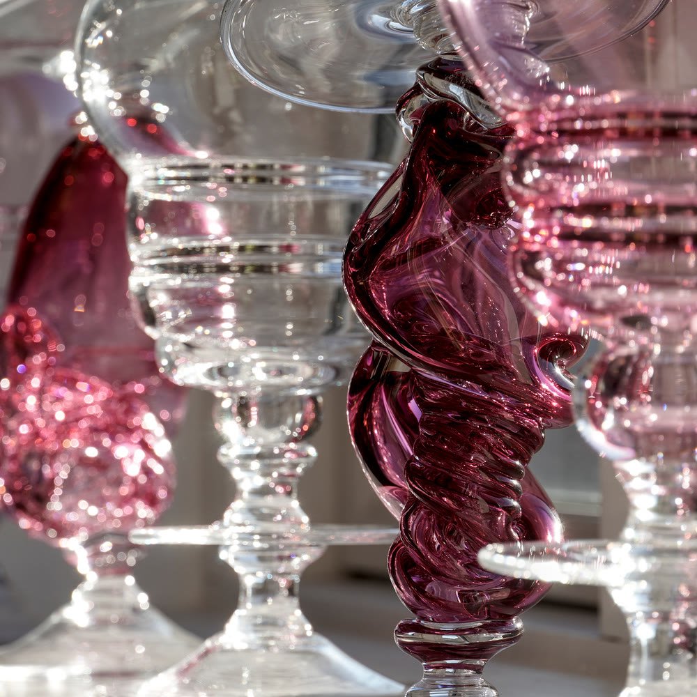 A cluster of footed vases in clear and cranberry glass with ribbed stems