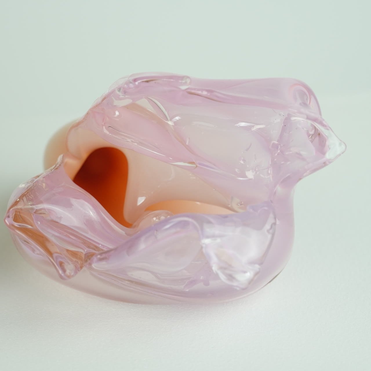 A pink glass form opening onto a warm orange interior