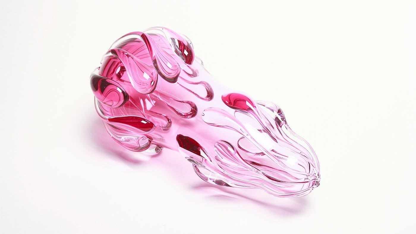 A pink glass form covered in teardrop protrusions, on white