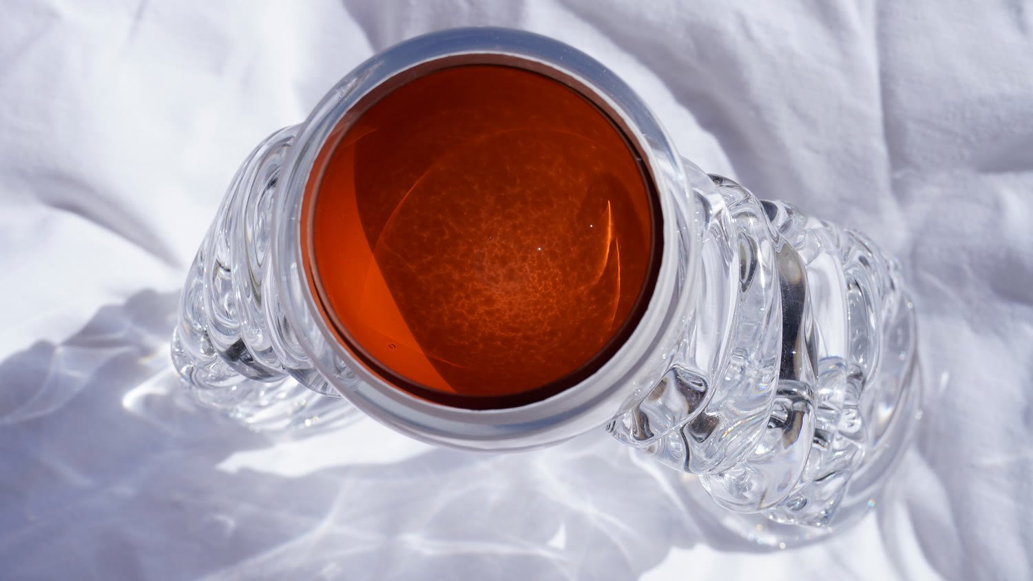 Looking down into a vase's terracotta interior, its ribbed clear base on white cloth