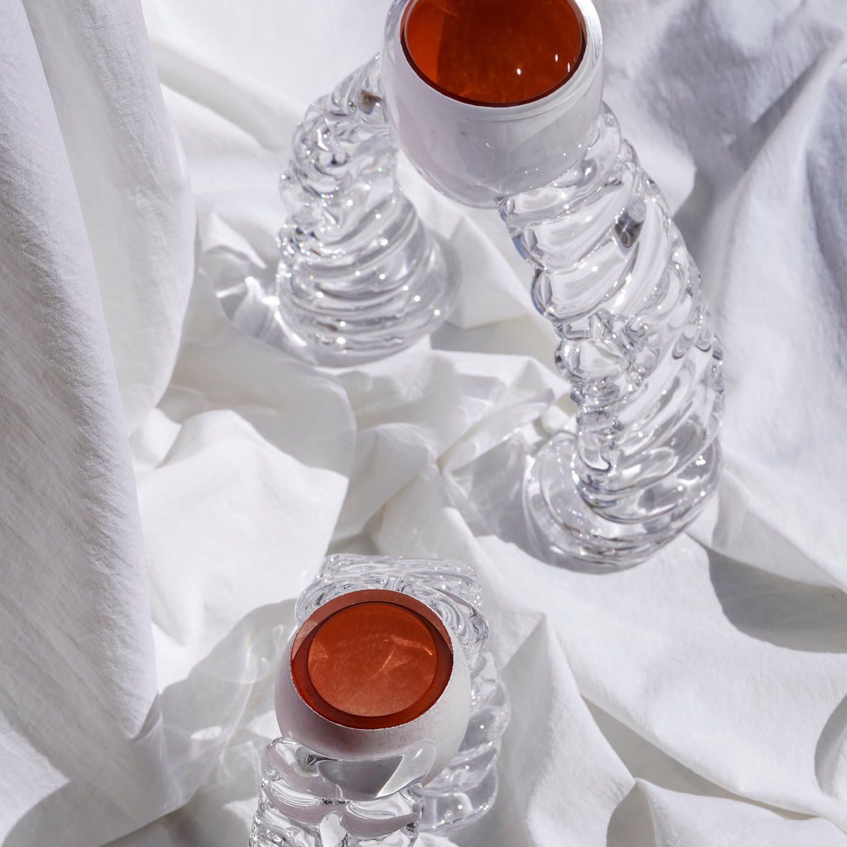Two vases on white cloth, terracotta mouths above ribbed clear bases